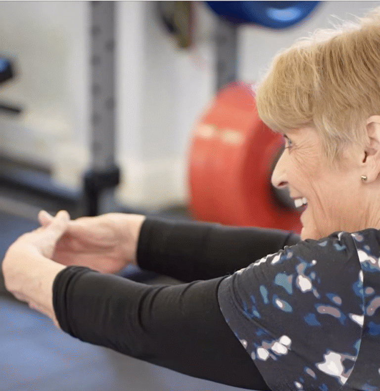 Wendy smiling while stretching her arms forward during a personal training session at The Training Gyms in St Albans.