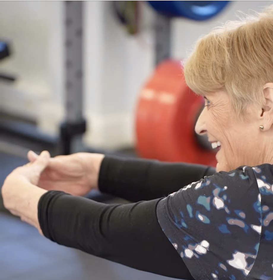 Wendy smiling while stretching her arms forward during a personal training session at The Training Gyms in St Albans.