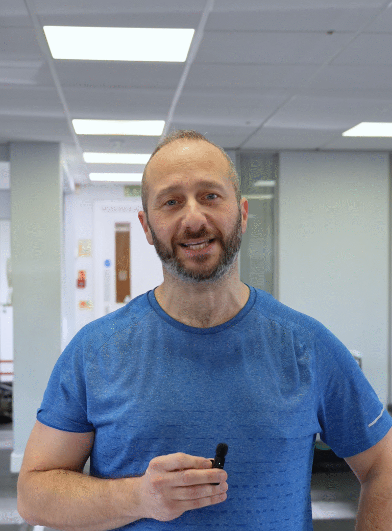 Andy, a smiling gym member wearing a blue T-shirt, standing confidently in a bright, modern training space at The Training Gyms in St Albans.
