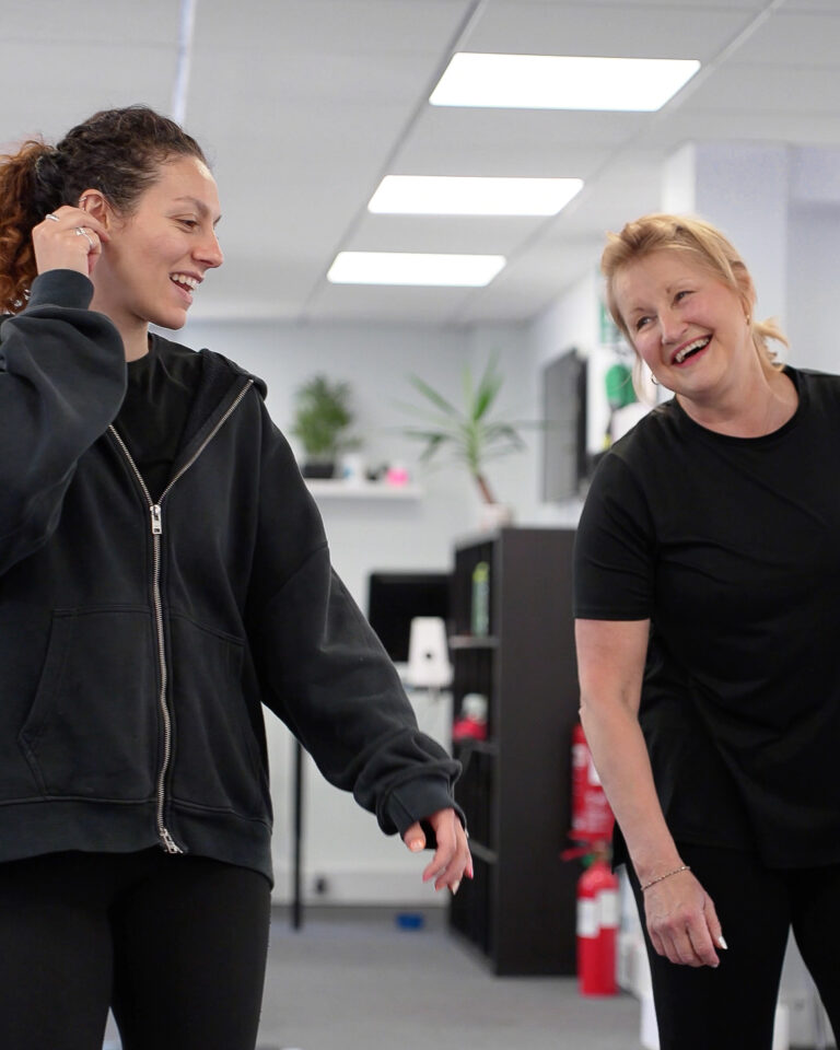 Two women smiling and chatting during a session at a personal training gym in St Albans, highlighting the supportive and friendly atmosphere.